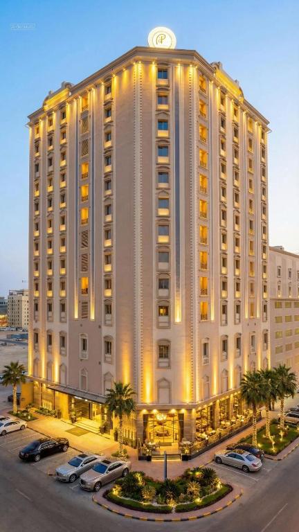 a large white building with cars parked in a parking lot at Ramee Rose Hotel in Manama