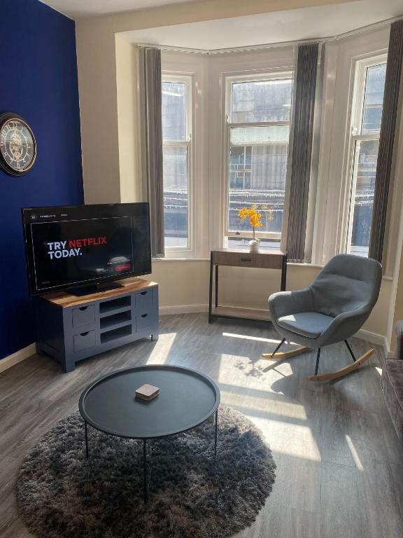 a living room with a tv and a chair and a table at Betty's Apartment- Metres From Train Station in Harrogate