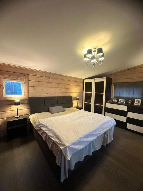 a bedroom with a large bed and a chandelier at Best Cottage in Ruokolahti