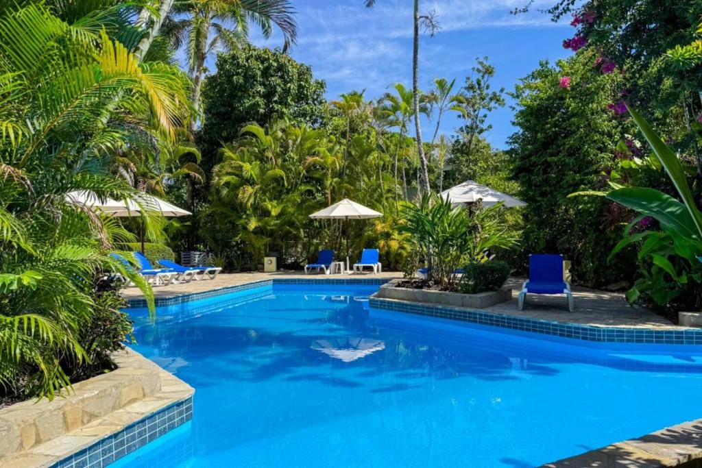 a pool at a resort with blue chairs and umbrellas at Renaissance Residence Cabarete in Cabarete
