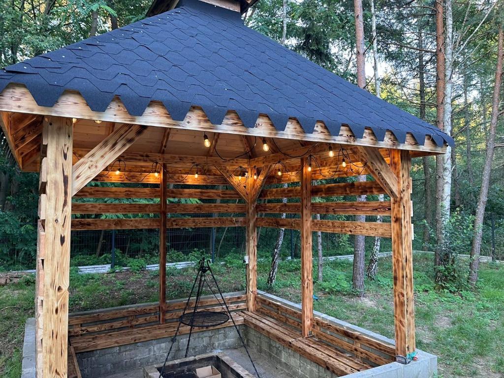 Leśna Grota na Roztoczu في Górecko Stare: شرفة خشبية مع سقف أسود