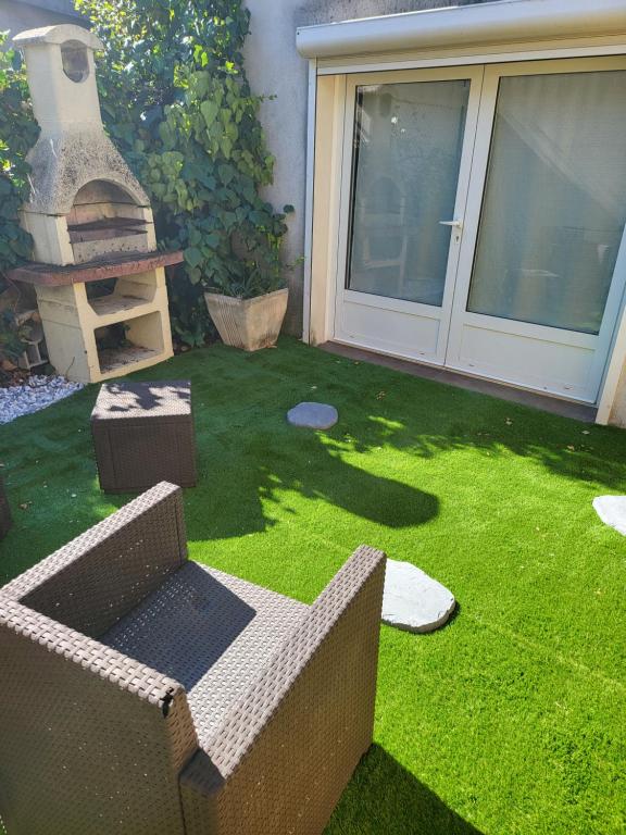 een tuin met een bank en een grill op het gras bij Loft Appartement Les Angles 30133 Possibilité jacuzzi in Les Angles Gard