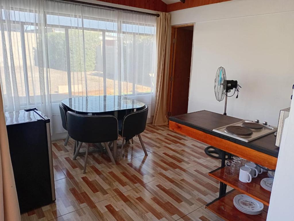 a dining room with a glass table and a window at Las Cabañas del Francés in Vallenar
