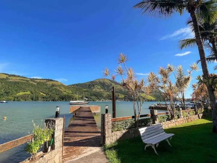 ein Holzsteg, der zu einem See mit einer Bank führt in der Unterkunft Angra dos Reis - Píer 600 casa 4 in Angra dos Reis