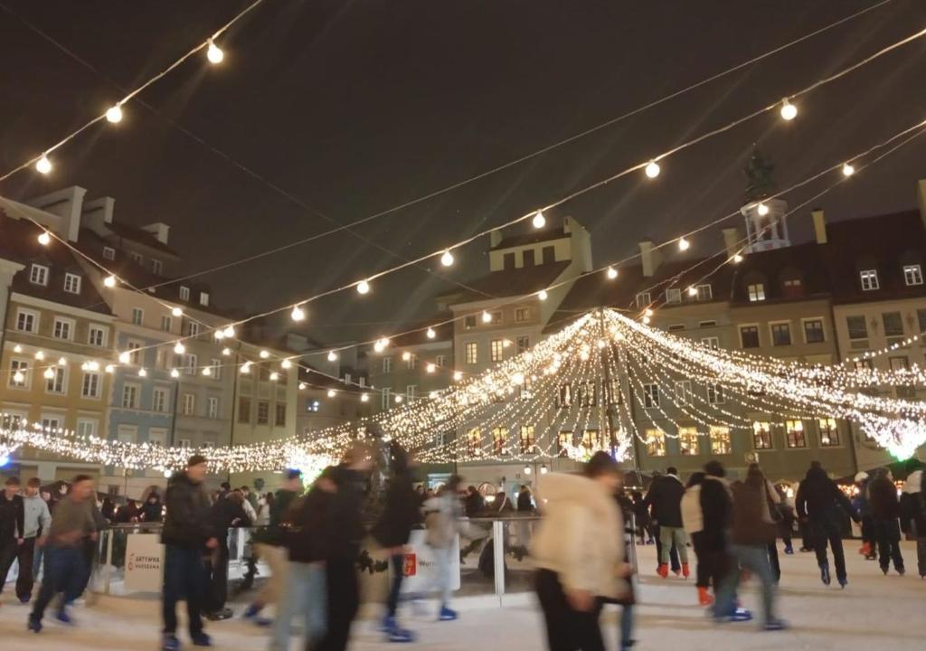 eine Gruppe von Menschen, die vor einem Gebäude mit Lichtern spazieren in der Unterkunft Studio Syreny in Warschau