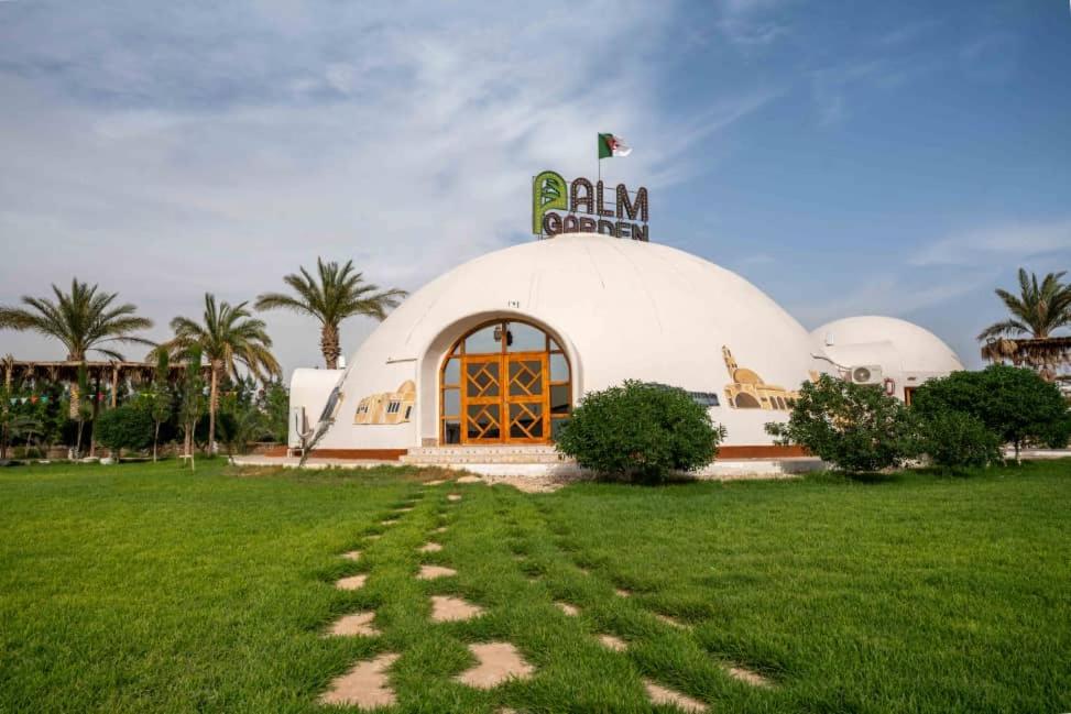 GuemarPalm Garden Souf的一座白色的大建筑,上面有旗帜