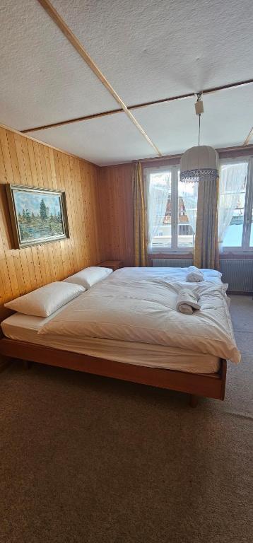 Cama grande en habitación con 2 ventanas en Alphenrose saxeten, en Saxeten