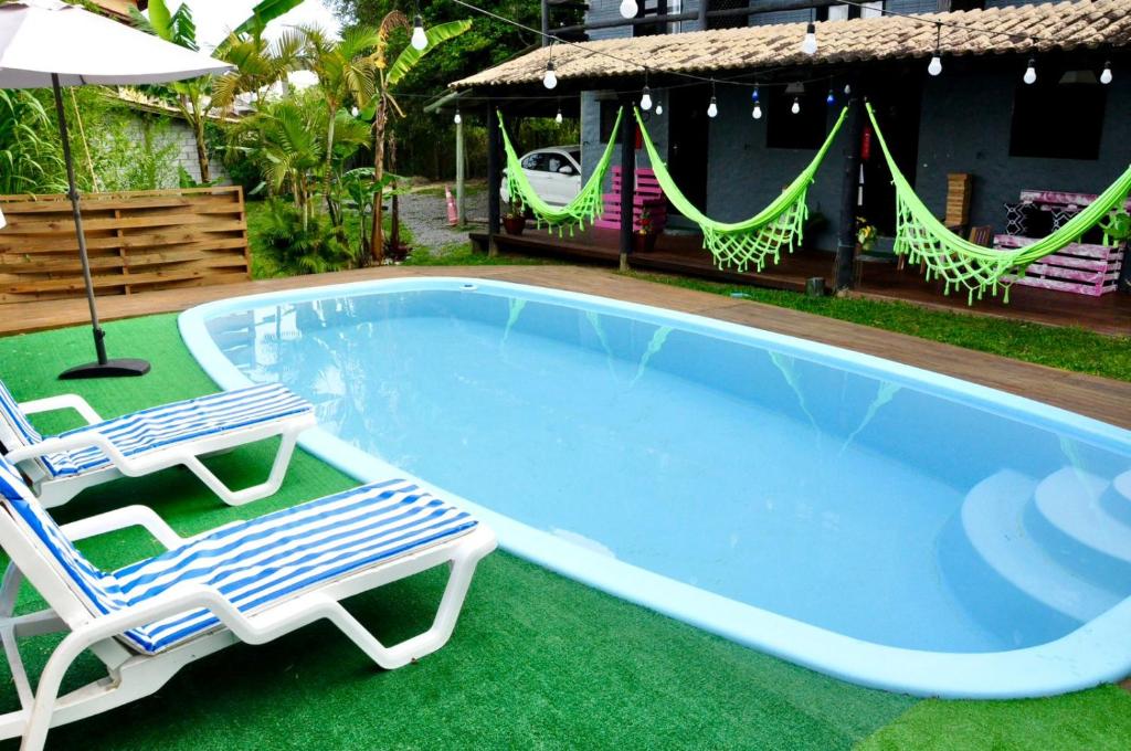 une piscine avec deux chaises et un parasol dans l'établissement Pousada pantera do rosa, à Imbituba