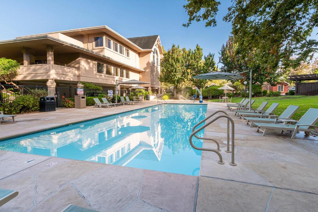 a swimming pool with chairs and a house at RiverPointe Napa Valley Resort in Napa