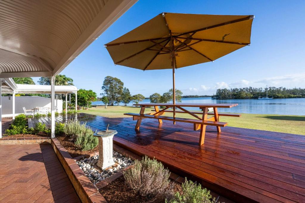 a wooden deck with a picnic table and an umbrella at Crystal Palms - Oceanstays - Riverside in Yamba