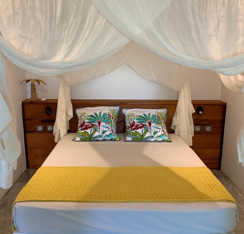 a bedroom with a canopy bed with two pillows at Hamakana gîte vue mer in Grand-Bourg