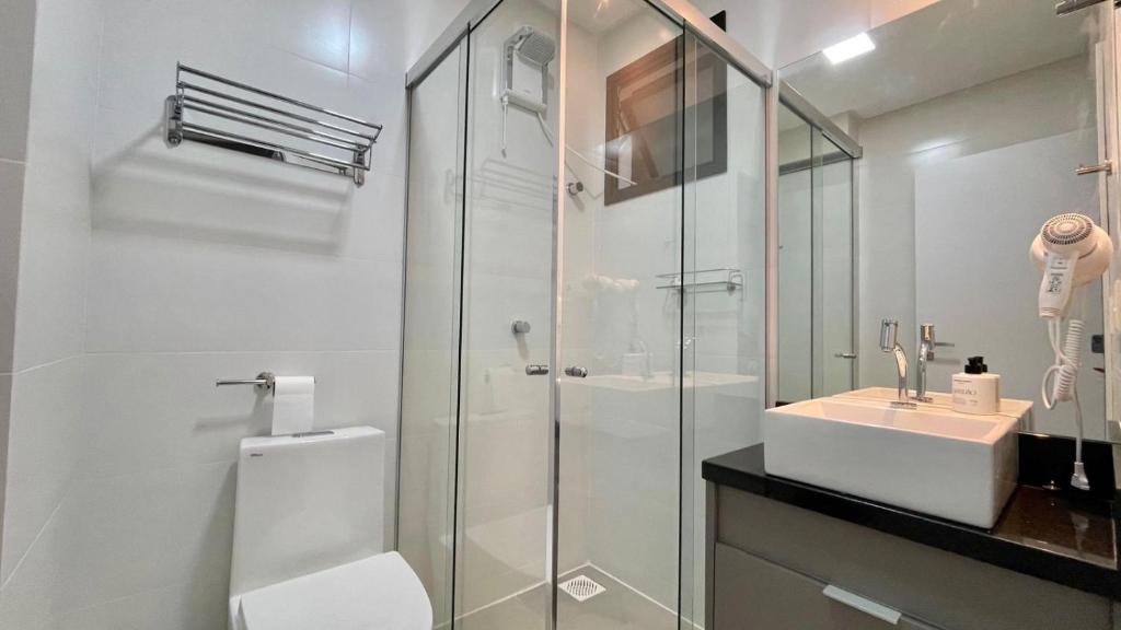 Un baño con inodoro, lavabo y ducha. en Apartamento vista Mar Piscina na Cobertura, en Itapema