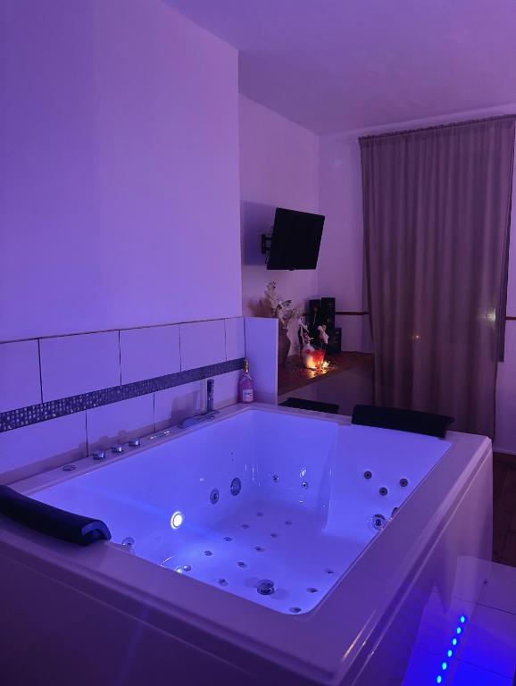 a large bath tub in a room with purple lighting at Nali Room in La Vespière