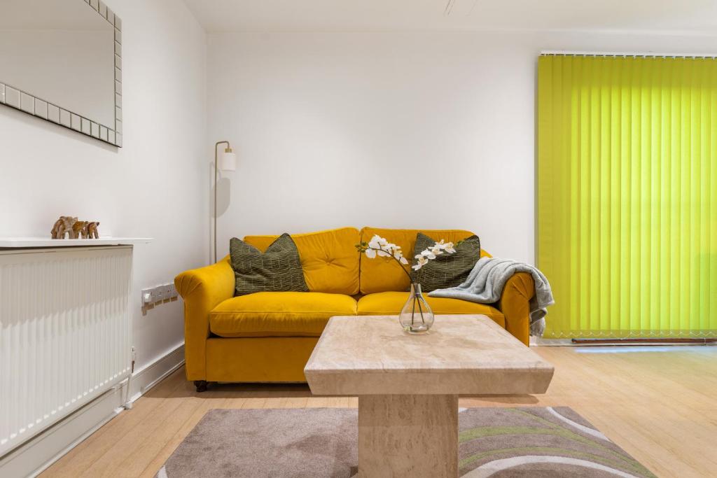a living room with a yellow couch and a table at Khayat Homes - The Ford in Chelmsford