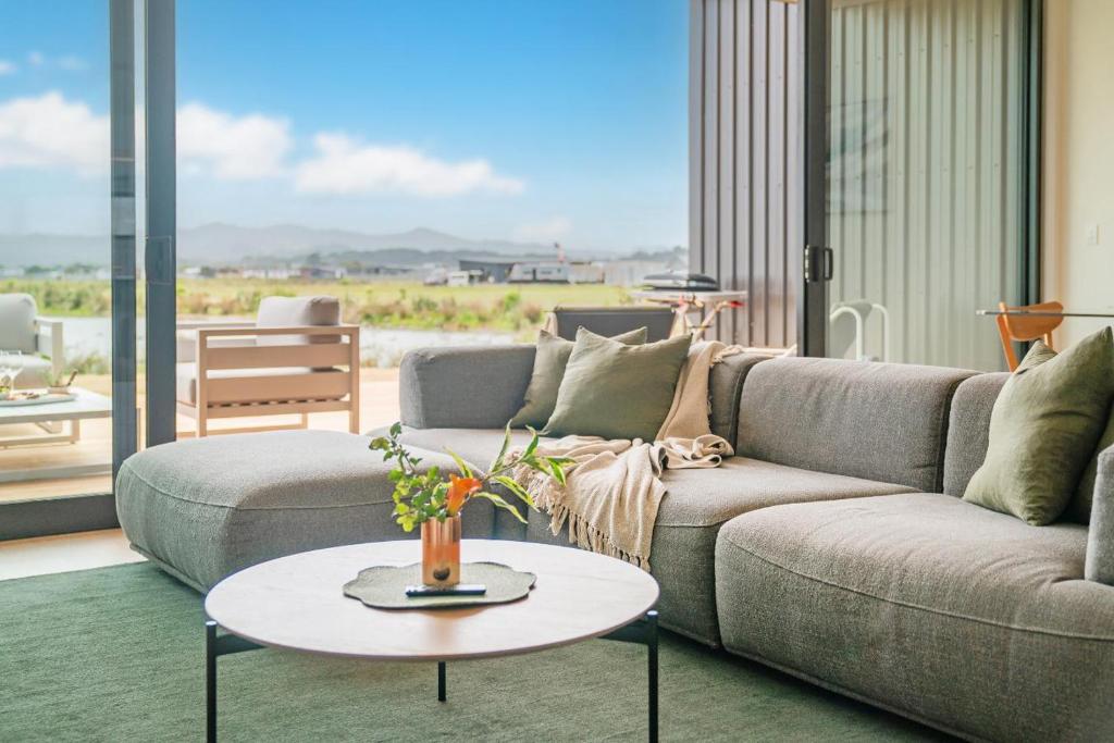 a living room with a couch and a table at Lakeside Retreat Matarangi - Deluxe Home with Sleep-out in Whitianga