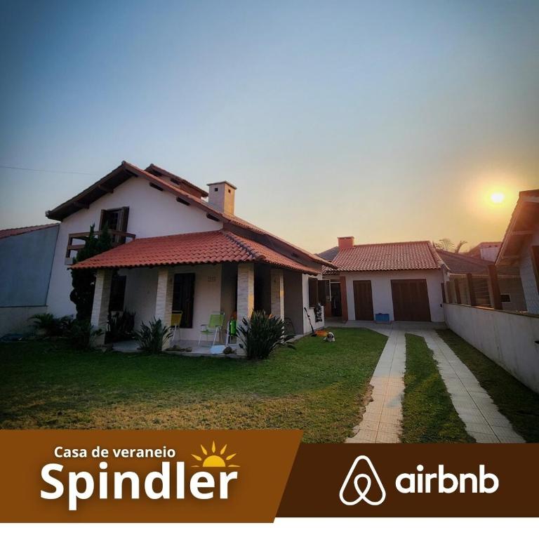 a house with the sun setting in the background at Spindler summer house in Tramandaí