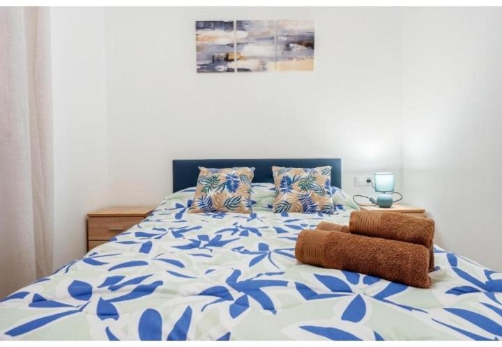 a bedroom with a bed with a blue and white comforter at Apartamentos de Miguel in Vinebre