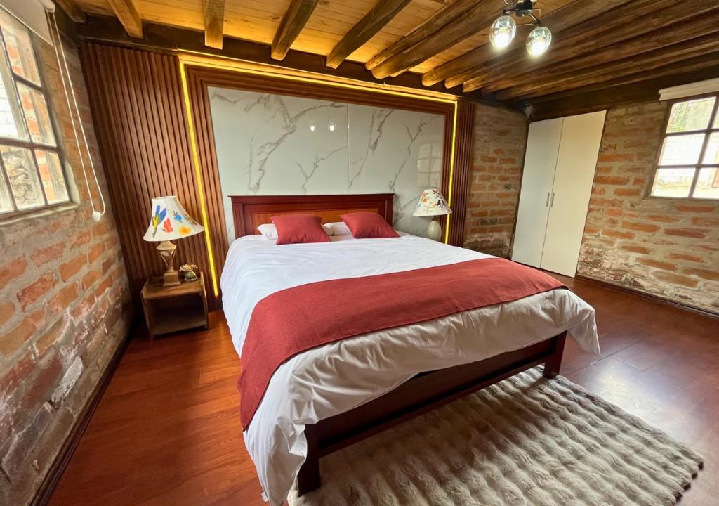 MalchinguíにあるCabaña en el Campo Malchinguí WIFI 24 horasのレンガの壁、大きなベッド付きのベッドルーム1室