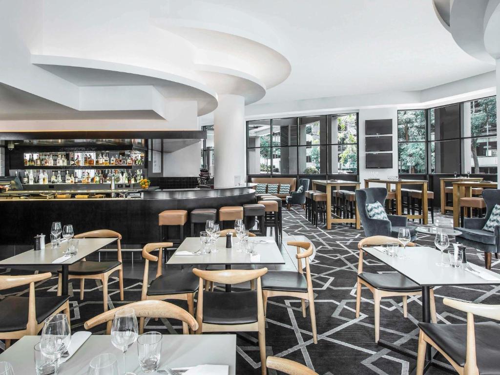 a restaurant with tables and chairs and a bar at Mantra Parramatta in Sydney