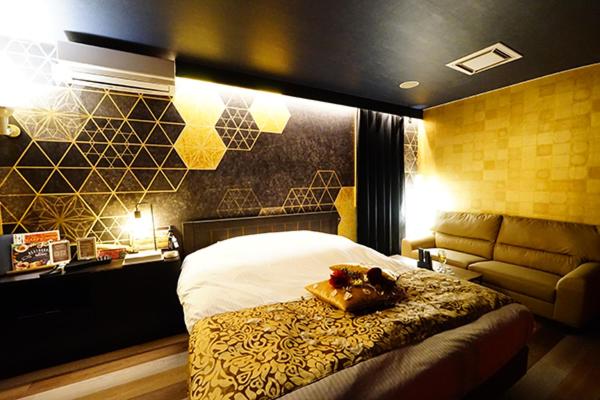 a hotel room with a bed and a couch at Hotel TOSCANA - Adult Only in Kanegasaki