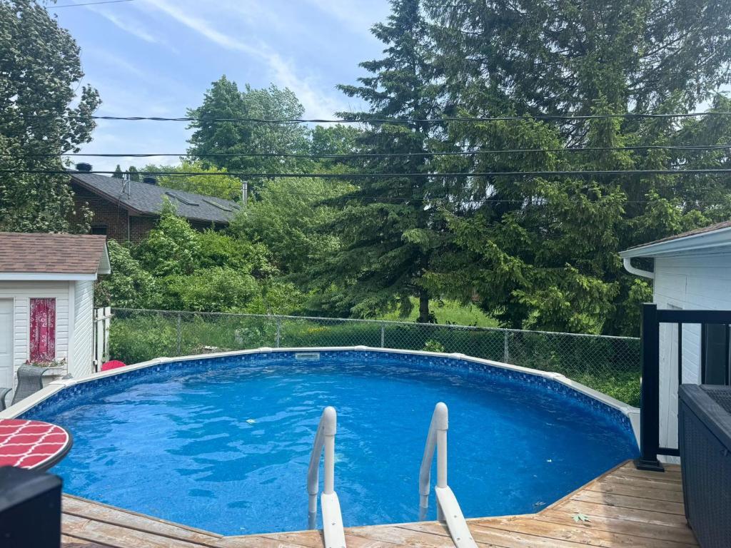einen großen blauen Pool auf einer Holzterrasse in der Unterkunft Amazing Home away from Home in Sainte-Catherine