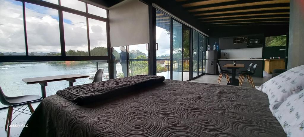 een slaapkamer met een bed, een tafel en ramen bij Villa Lake Blue in El Peñol