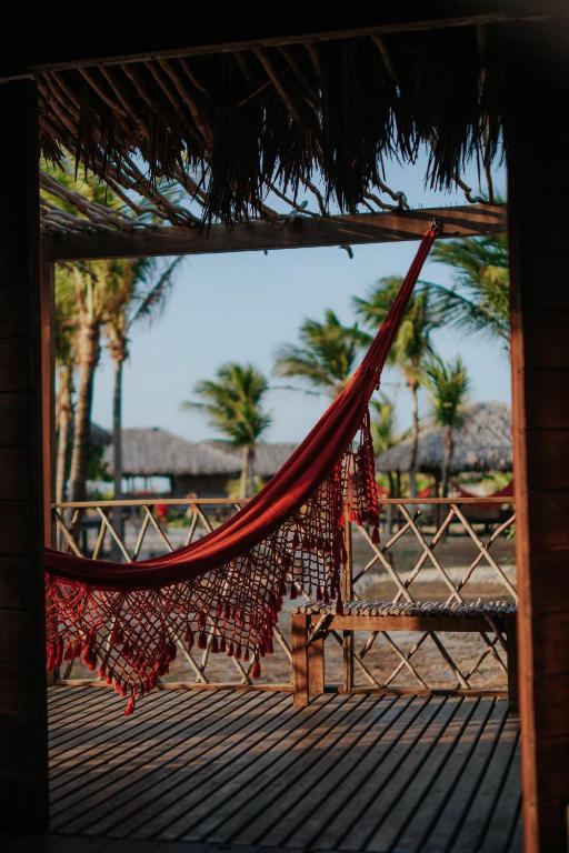 a hammock on a beach with palm trees in the background at Vila Guará in Atins