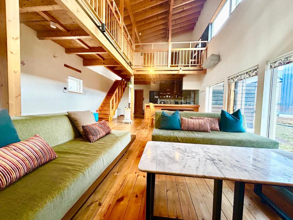 a living room with two green couches and a table at Ajito Niseko in Kutchan