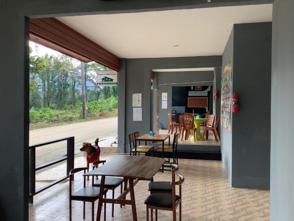 a dining room with a table and chairs and a kitchen at Evergreen Guest House in Khao Sok
