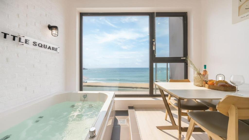 Un baño con bañera y una mesa y una mesa y una ventana. en Goseong Littlesquare Oceanview Pension, en Goseong