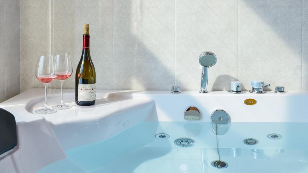 una bottiglia di vino e due bicchieri su una vasca da bagno di Buan TomynSpa Pension a Buan