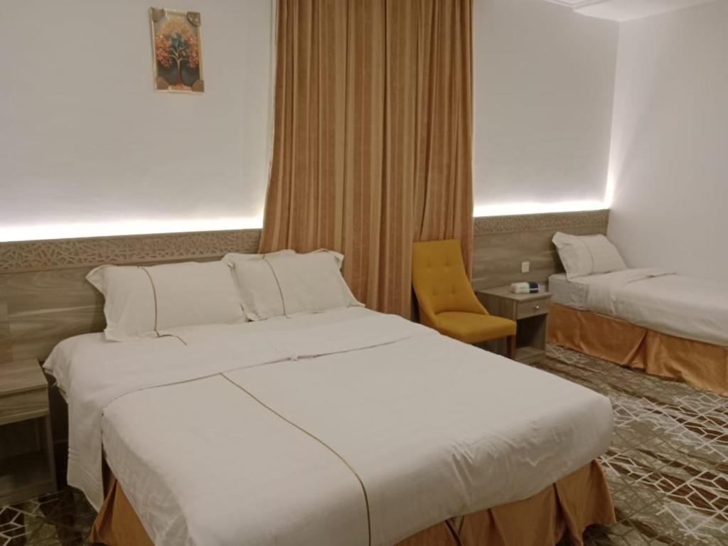ein Hotelzimmer mit zwei Betten und einem Stuhl in der Unterkunft فندق اوتاد البدر الششه in Al Khansāk