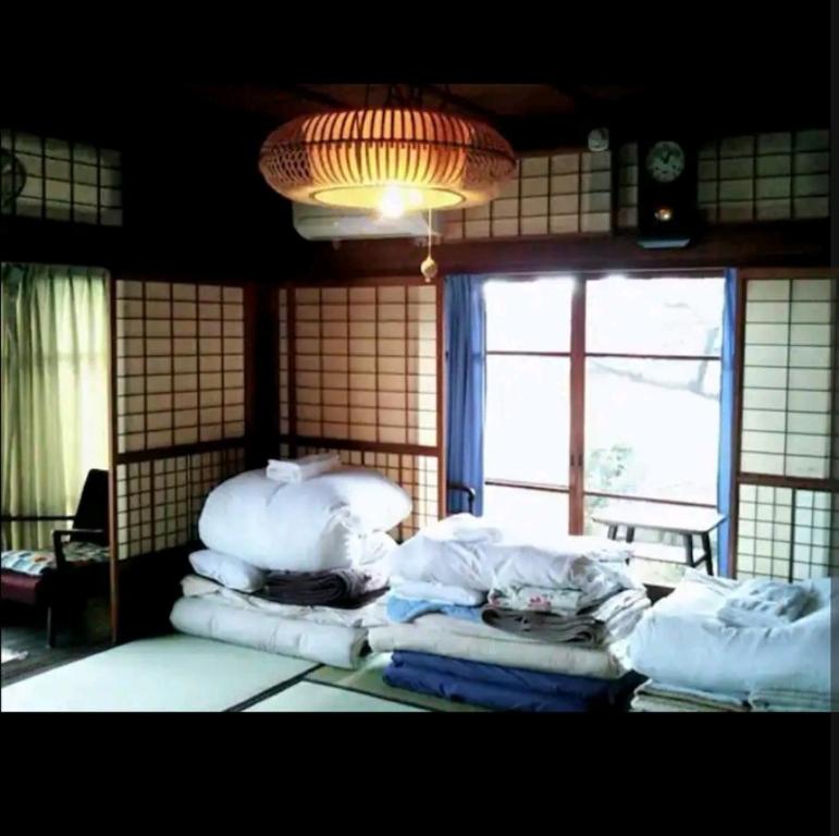 una habitación con una pila de almohadas blancas y una ventana en O19 Tea Celemony Villa, en Onomichi