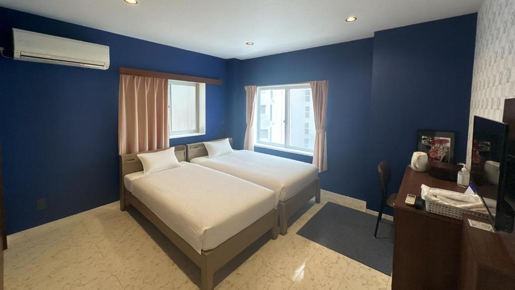 um quarto com uma cama e uma parede azul em Kawabata Ryokan Takehara by Tabist em Takekara