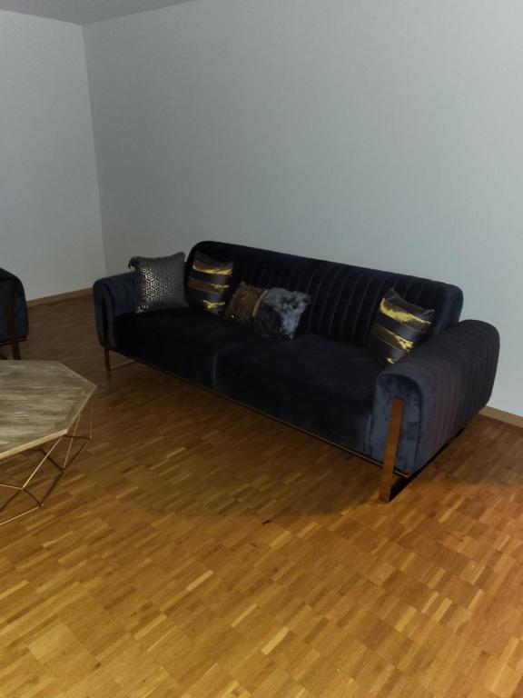 ein schwarzes Sofa in einem Zimmer mit Holzboden in der Unterkunft Le relais du Marronnier in Grandsivaz