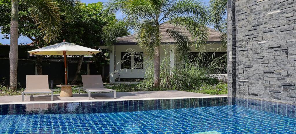 Nua Tone Pool Villa I Mountain View I Bangtao Beach في Ban Thalat Choeng Thale: كرسيين ومظله بجانب مسبح