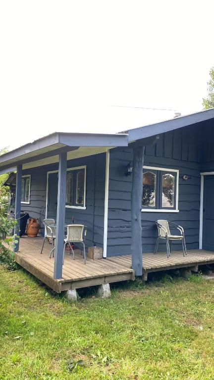 Cabaña Arte Patagonia في بويوهو: منزل أزرق اللون ذو شرفة عليها كرسيان