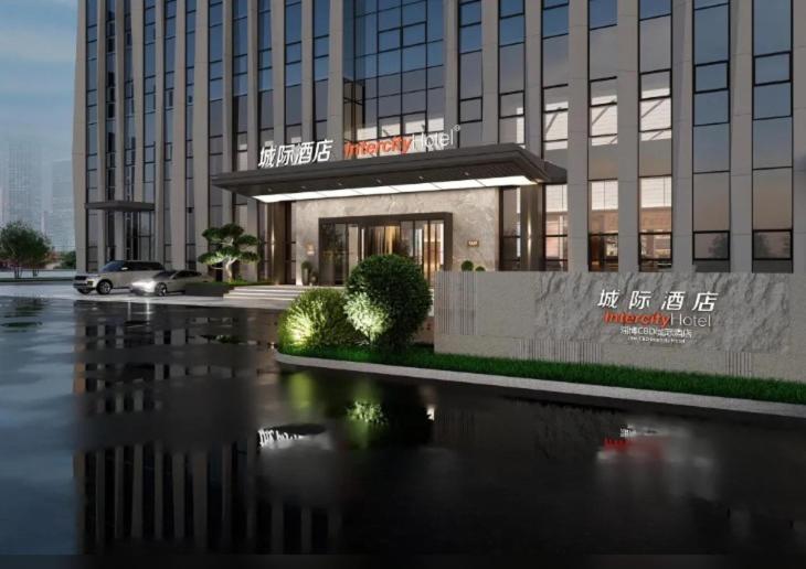 a large building with a reflection in a body of water at Intercity Hotel Zibo in Zibo