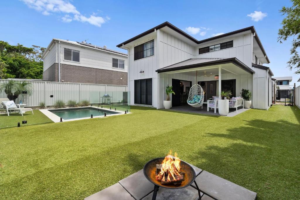 a backyard with a fire pit in front of a house at Holiday Haven on Spoonbill Pet Friendly with Pool in Kingscliff