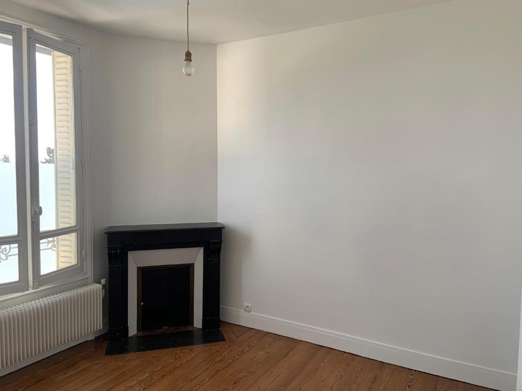 een witte kamer met een open haard en een raam bij Petite Maison in Châtenay-Malabry