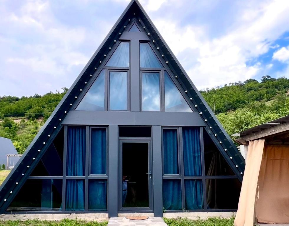 a house with a triangular roof with blue curtains at Green Villa Resort Small Gray in Dilijan