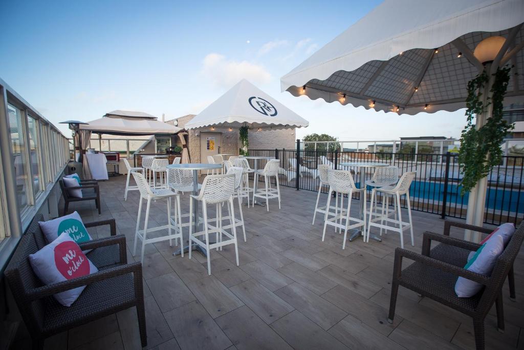 a patio with white chairs and tables and umbrellas at Gladstone Reef Hotel Motel in Gladstone