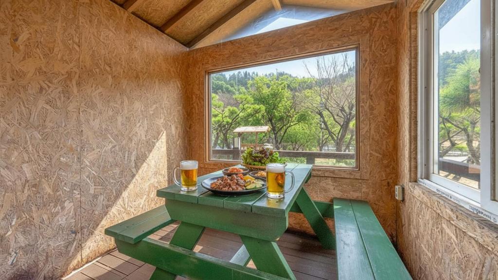 a table with a bowl of food and two glasses of beer at Gapyeong Maplein Pension in Pocheon