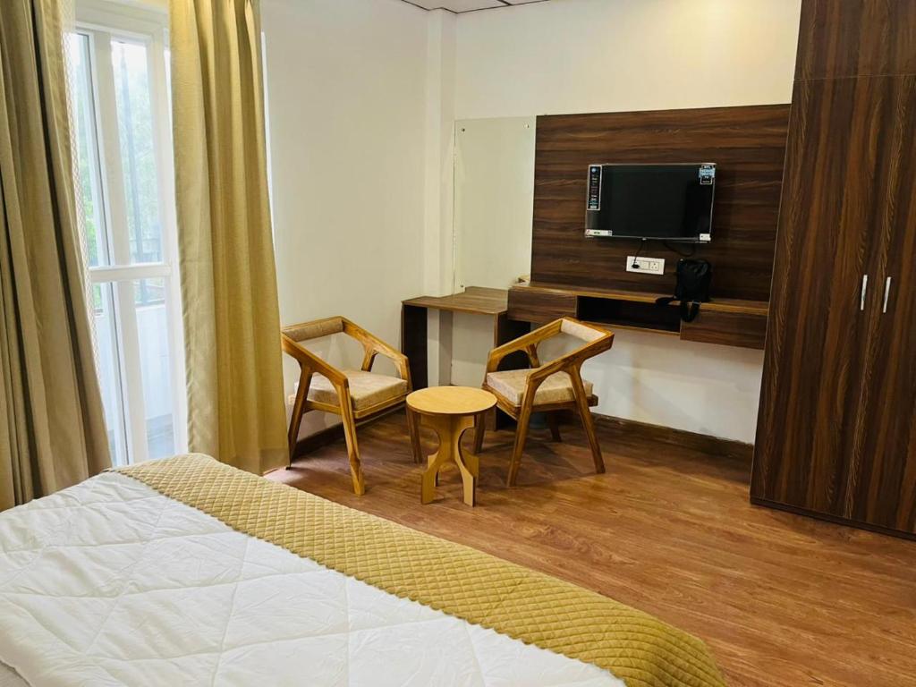 una camera d'albergo con un letto, due sedie e un tavolo di Simran Aura Resort a Dehradun