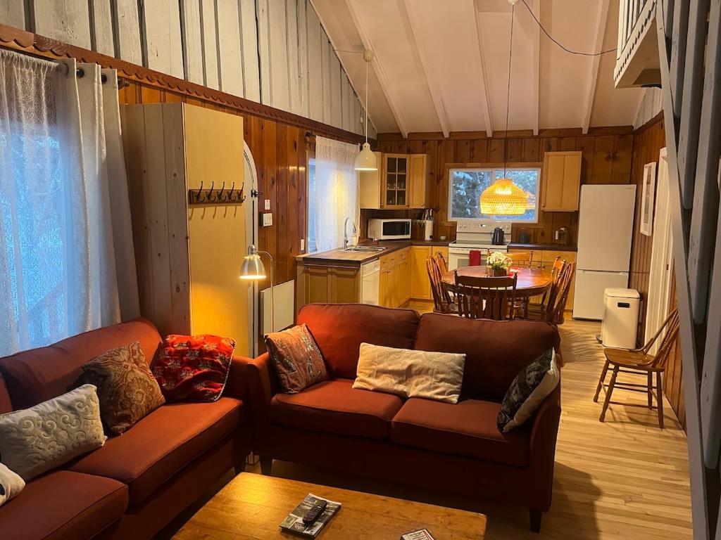 uma sala de estar com um sofá e uma cozinha em Chalets Village Suisse de Val-David em Val-David