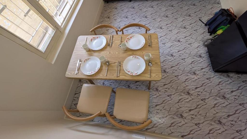 a wooden table with chairs and plates on it at Apartment in kathmandu in Kathmandu