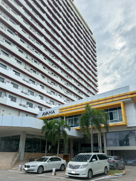 two cars parked in front of a large building at Avana Residence in Bangna