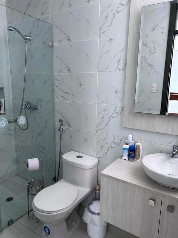 Un baño con inodoro, lavabo y ducha. en departamento salinas, en Salinas