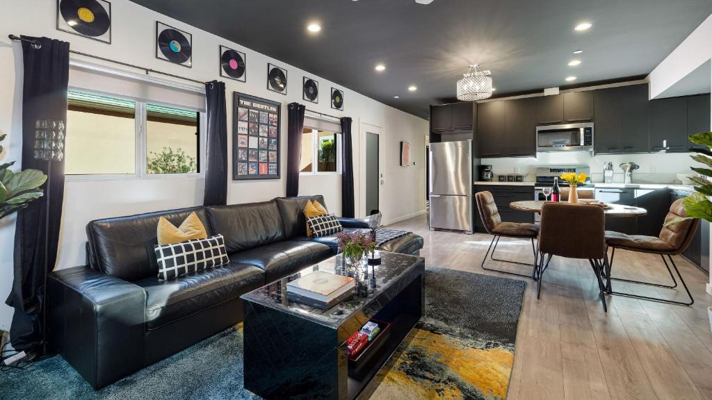 a living room with a leather couch and a kitchen at Rock n Roll by AvantStay Vibey 2BDR in Prime Hollywood Steps to Attractions in Los Angeles