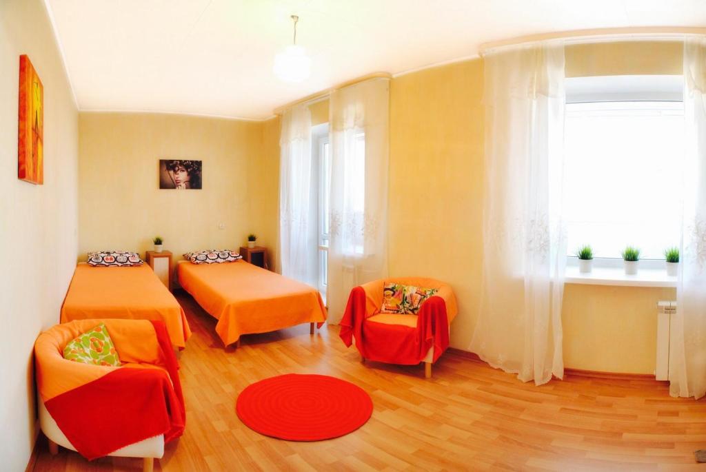 ハバロフスクにあるApartments on Sheronova 10 Orangeのベッド2台と椅子、窓が備わる客室です。